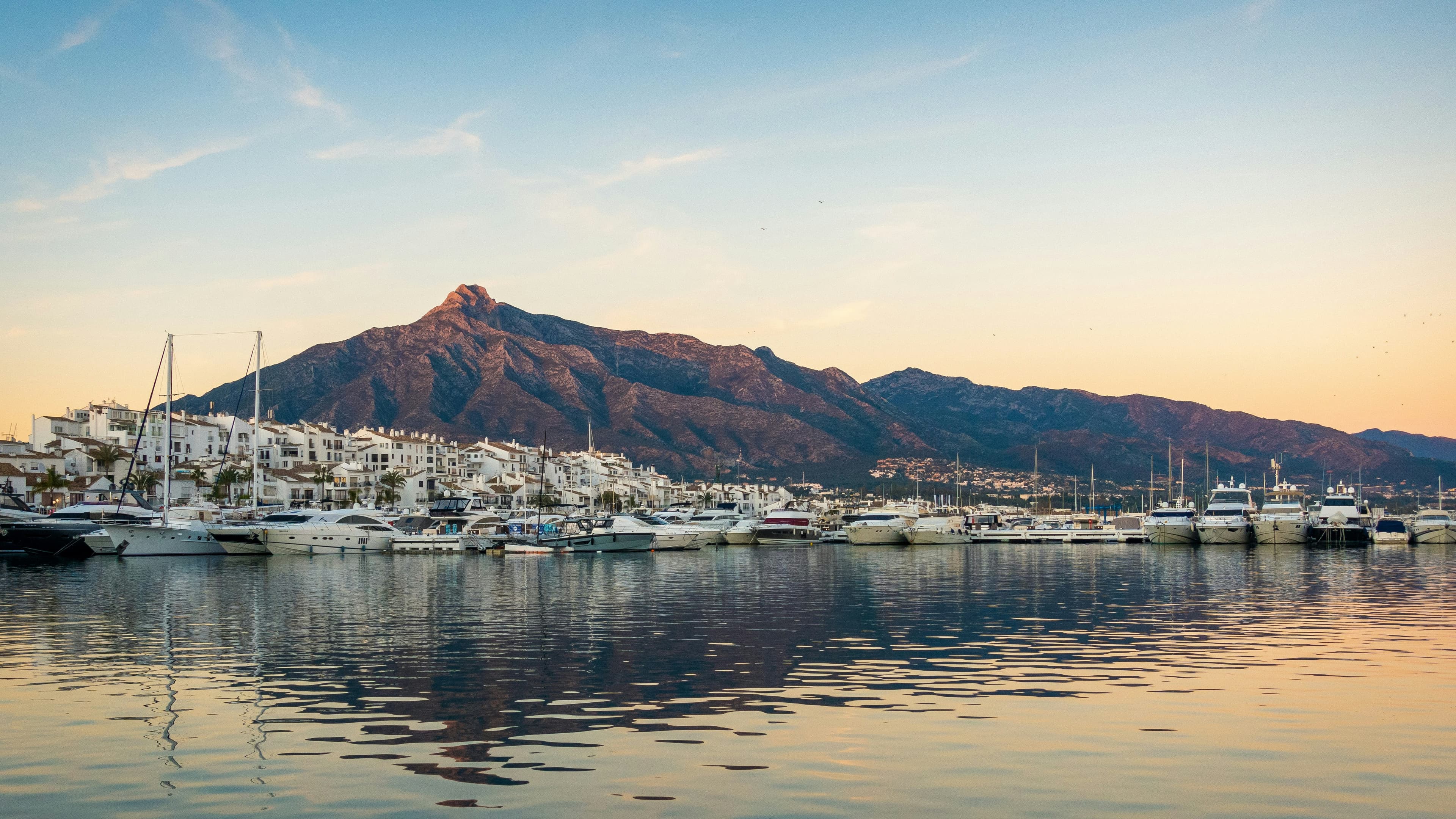 White boats moored on the Marbella seafront with the Sierra Blanca mountains behind