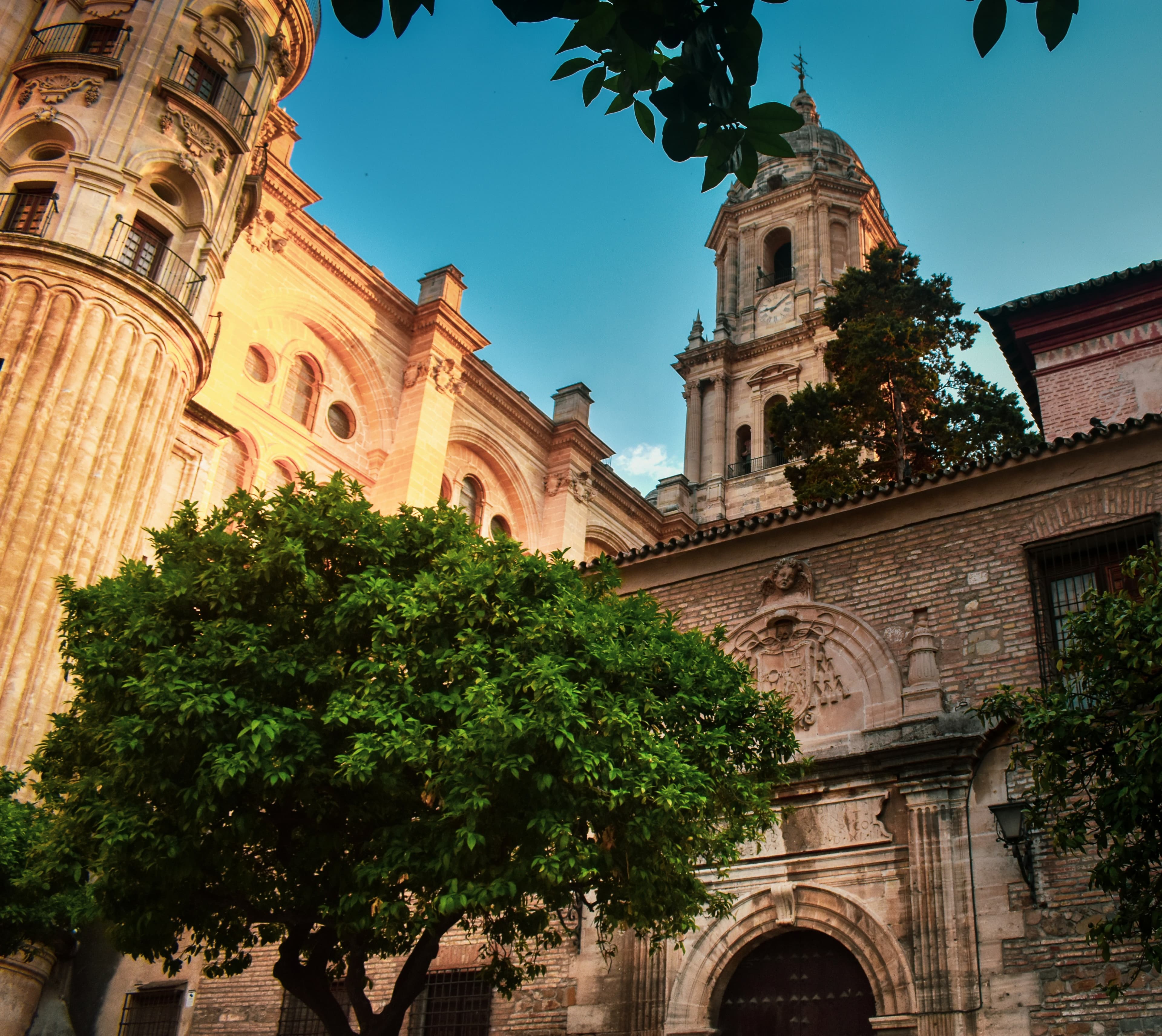 The stonework of Málaga Cathedral under a bright blue sky
